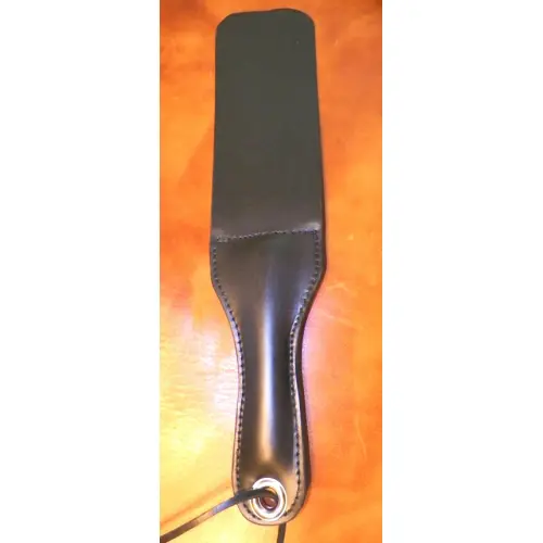 A Black Leather Paddle With String Hole on a Table